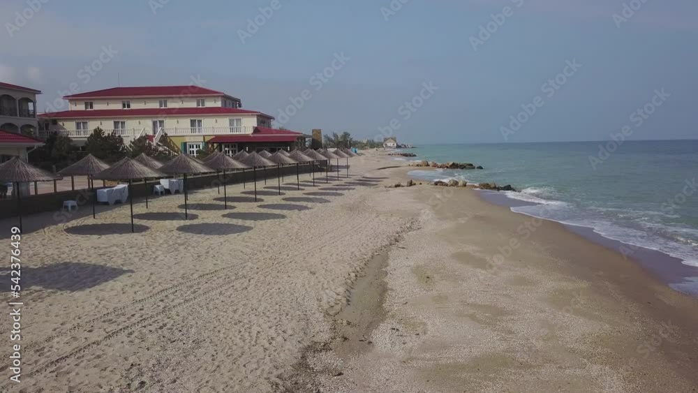 Aerial view of straw umbrellas on the beach. Ocean waves washing sandy shore. Tranquil coast line of a luxury resort. Aerial view of straw umbrellas on the beach. Ocean waves washing sandy shore. Tranquil coast line of a luxury resort.