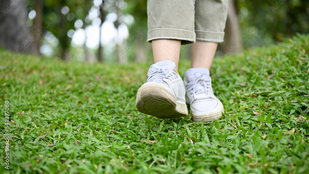 A hipster woman in casual clothes and white sneakers strolling in the garden. cropped A hipster woman in casual clothes and white sneakers strolling in the garden. cropped