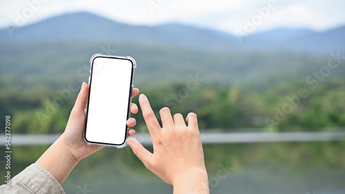 Fototapeta Naklejka Na Ścianę i Meble -  Young Asian female using her modern smartphone to take a picture of lake and mountain