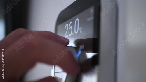 A woman adjusts smart thermostat gadget at home photo