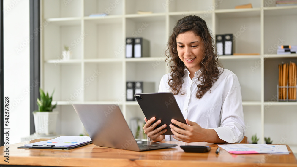 Beautiful millennial Caucasian businesswoman using her tablet at her office desk. Beautiful millennial Caucasian businesswoman using her tablet at her office desk.