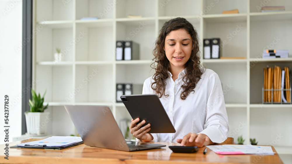 Caucasian businesswoman or female accountant using calculator, working on her tasks Caucasian businesswoman or female accountant using calculator, working on her tasks