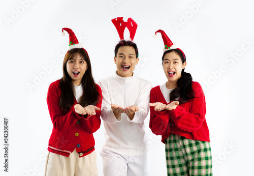Group of three asian people in sweater holding gift boxes posing excited and surprised white background. Merry Christmas.
