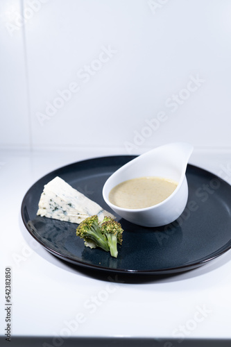blue cheese broccoli soup white bowl elegant black plate portion