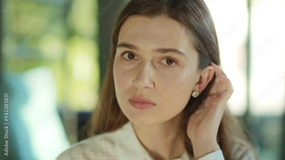 Portrait of an attractive young woman turning her head and looking at the camera serious in the sunlight office. Successful businesswoman. Motivated employer. Concentrate worker. Slow motion Portrait of an attractive young woman turning her head and looking at the camera serious in the sunlight office. Successful businesswoman. Motivated employer. Concentrate worker. Slow motion