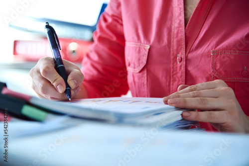 Accountant or businesswoman with pen checking business report