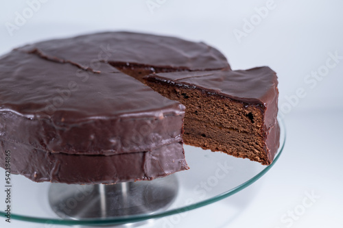 sacher torte chocolate Viena brown portion slice white background, cristal plate