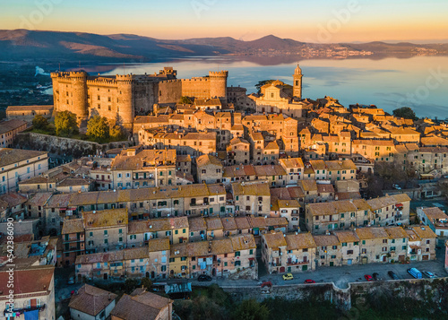 Sunset Panoramic view of the old town of Bracciano perched above the calm waters of Lake Bracciano, near Rome, Italy - Orsini-Odescalchi castle and the village lit by the golden hour light