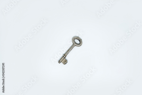 Photo of a house key made of chrome plated metal isolated in white background © adelukmanulhakim