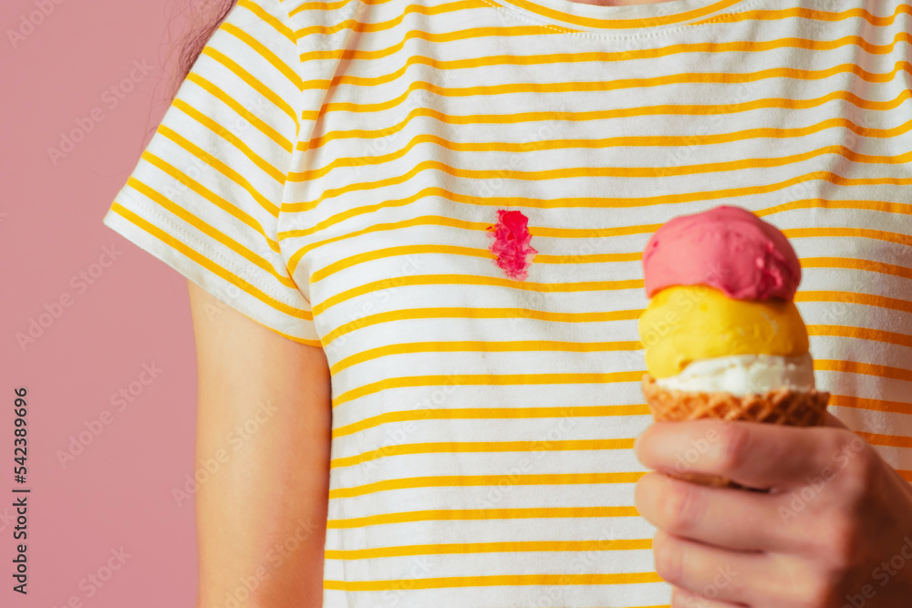 Spilling creamy strawberry ice cream on clothes. A girl's hand holding a ice cream cone with three scoops of different flavor on a pink background. isolated