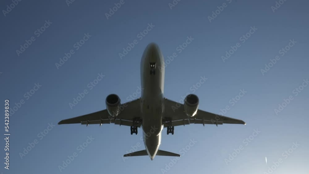 Plane flying overhead closely followed to silhouette, sun flare and slow motion. Plane flying overhead closely followed to silhouette, sun flare and slow motion.