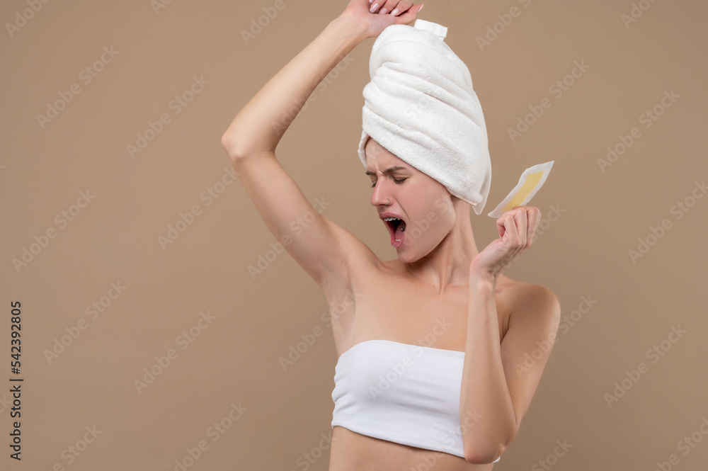 Young woman doing hair removing procedures and feeling upleased Young woman doing hair removing procedures and feeling upleased