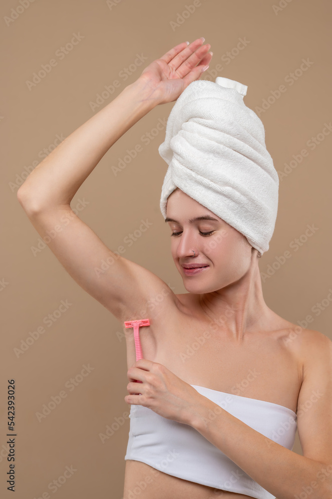 Young woman shaving underarms area Young woman shaving underarms area