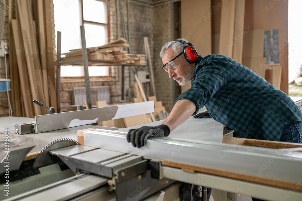 Carpenter in ear protectors working in a worshop Carpenter in ear protectors working in a worshop