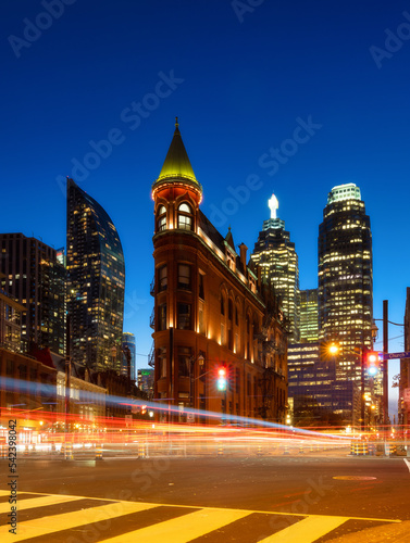 Canada, Toronto. The famous Gooderham building and the skyscrapers in the background. View of the city in the evening. Blurring traffic lights. Modern and ancient architecture. Night city. © biletskiyevgeniy.com