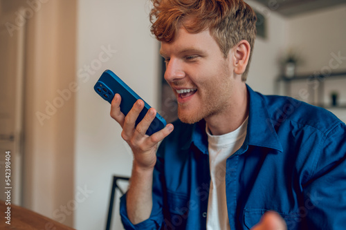 An excited man recording a voice mesage after reading good news photo