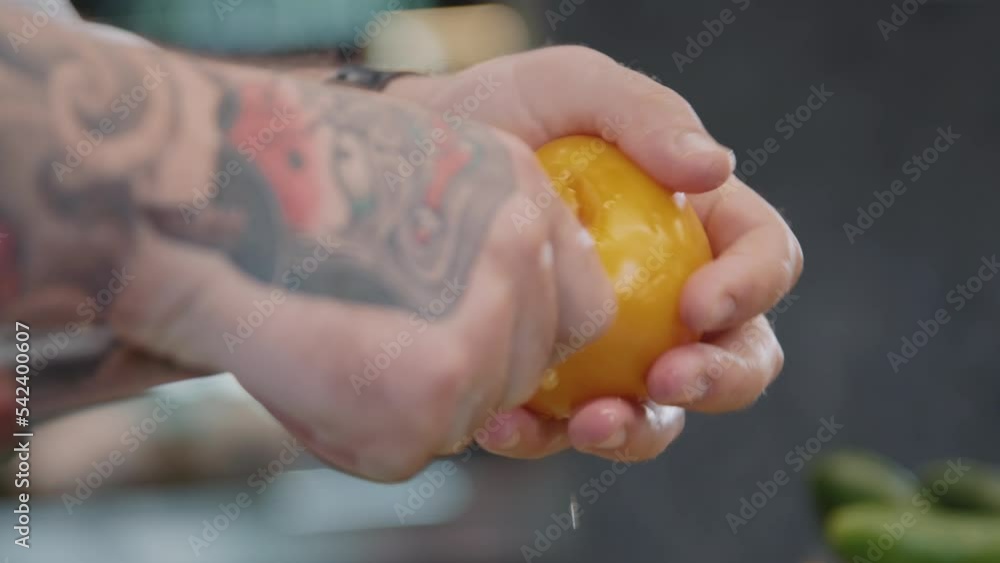 Cook holding knife in hand, cutting yellow tomato. Close-up view of hands of chef cooking meal with fresh vegetable. Healthy food concept. Indoor Cook holding knife in hand, cutting yellow tomato. Close-up view of hands of chef cooking meal with fresh vegetable. Healthy food concept. Indoor