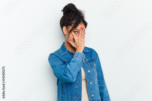 Young african american woman isolated blink at the camera through fingers, embarrassed covering face. © Asier