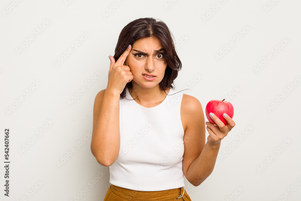 Young Indian woman holding an apple isolated on white background showing a disappointment gesture with forefinger. Young Indian woman holding an apple isolated on white background showing a disappointment gesture with forefinger.