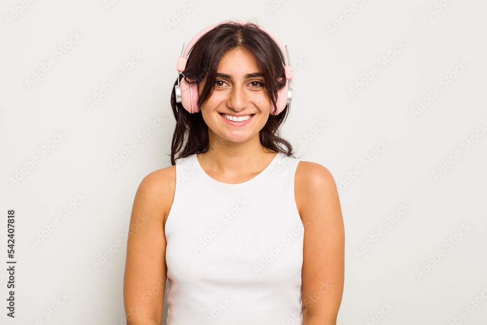 Young Indian woman wearing headphones isolated on white background happy, smiling and cheerful. Young Indian woman wearing headphones isolated on white background happy, smiling and cheerful.