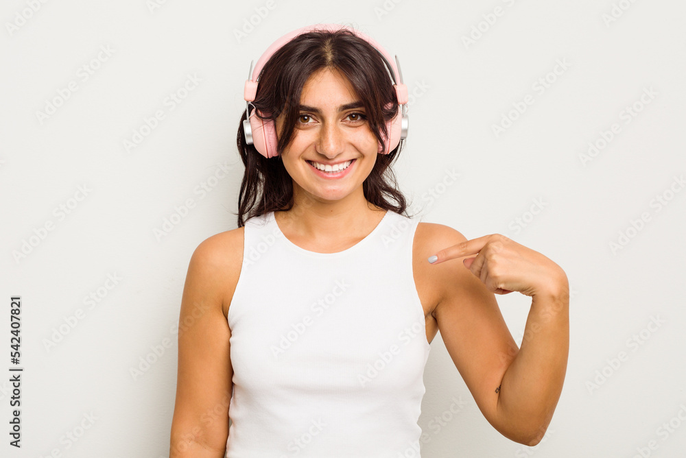 Young Indian woman wearing headphones isolated on white background person pointing by hand to a shirt copy space, proud and confident Young Indian woman wearing headphones isolated on white background person pointing by hand to a shirt copy space, proud and confident