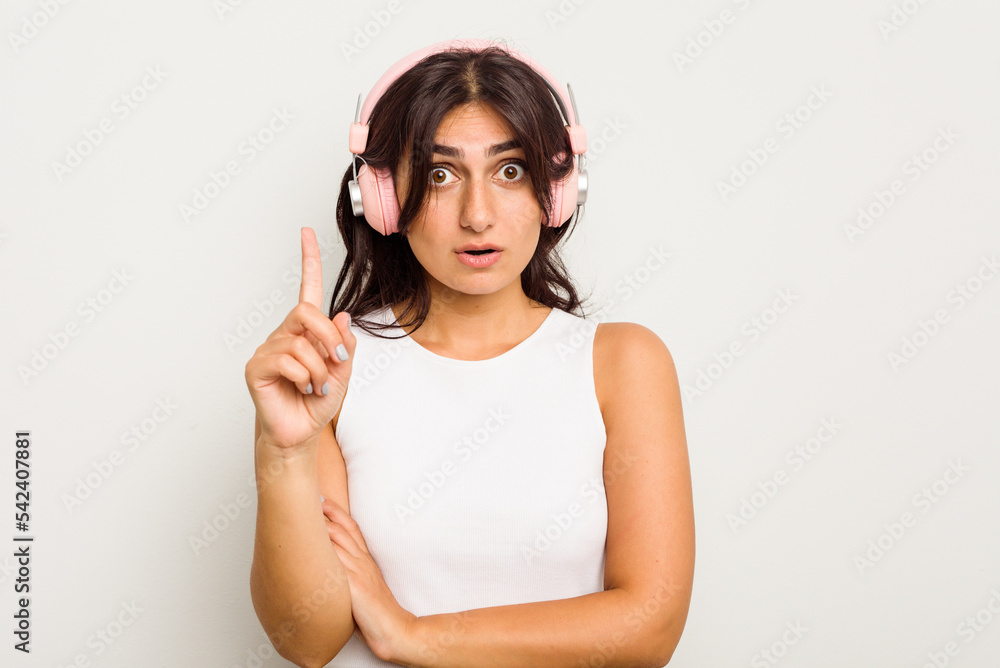 Young Indian woman wearing headphones isolated on white background having some great idea, concept of creativity.