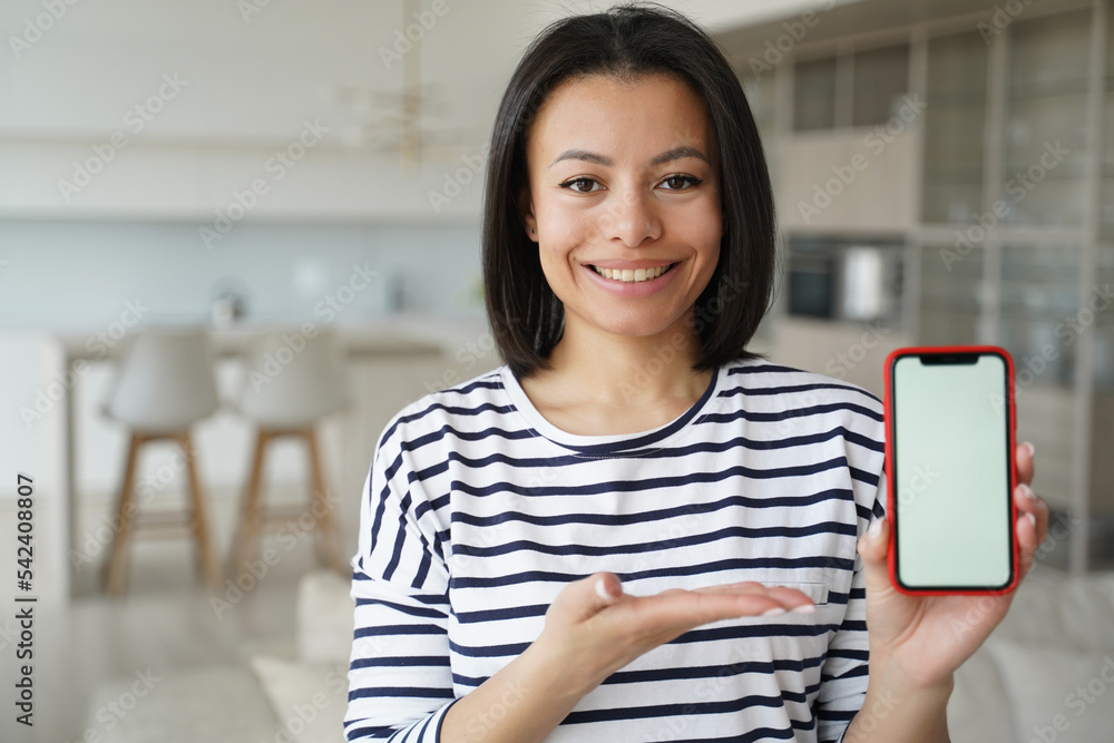 Smiling female showing smartphone with mock up blank screen at home. Mobile apps advertisement Smiling female showing smartphone with mock up blank screen at home. Mobile apps advertisement