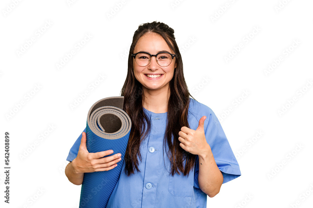 Young caucasian physiotherapist woman holding a mat isolated isolated on green chroma background smiling and raising thumb up Young caucasian physiotherapist woman holding a mat isolated isolated on green chroma background smiling and raising thumb up