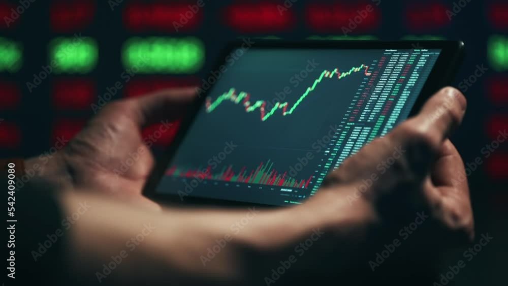 Stock market candles and information of exchange with data of price on the tablet screen. Financial indexes change up and down over time. Concept of trading cryptocurrency assets and bitcoin