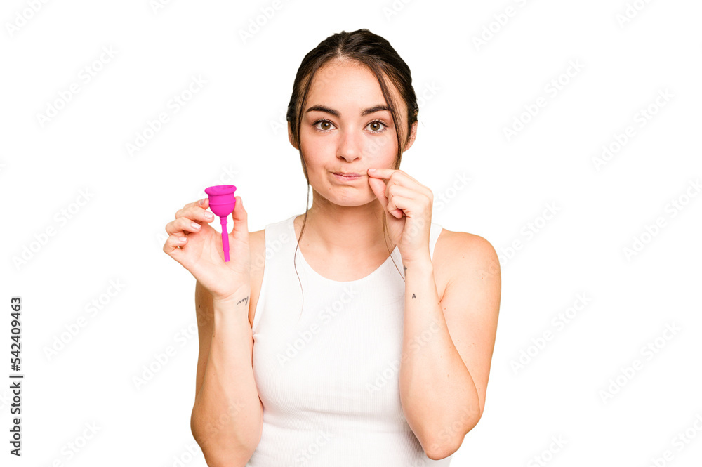 Young caucasian woman holding menstrual cup isolated on green chroma background with fingers on lips keeping a secret. Young caucasian woman holding menstrual cup isolated on green chroma background with fingers on lips keeping a secret.