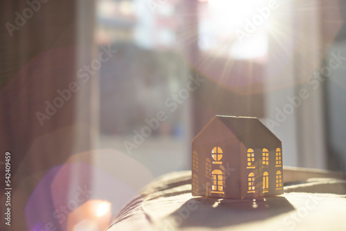 A white beautiful paper house illuminated by sunlight with a nice flare. Hygge feeling.