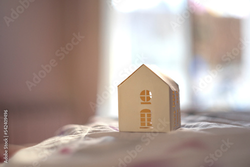 Tea light house on a white surface with a blurred horizontal background
