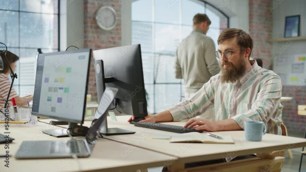 Portrait of Creative Bearded White Man with Glasses Focused While Using Computer in Bright Spacious Office. Marketing Manager Building a New Strategy. Dolly Shot. Portrait of Creative Bearded White Man with Glasses Focused While Using Computer in Bright Spacious Office. Marketing Manager Building a New Strategy. Dolly Shot.