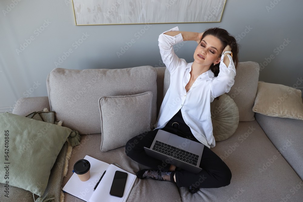 Young woman sitting on the couch and resting after a day at home. Remote work during a pandemic Young woman sitting on the couch and resting after a day at home. Remote work during a pandemic