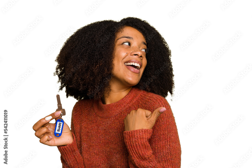 Young African american woman holding home keys isolated points with thumb finger away, laughing and carefree. Young African american woman holding home keys isolated points with thumb finger away, laughing and carefree.