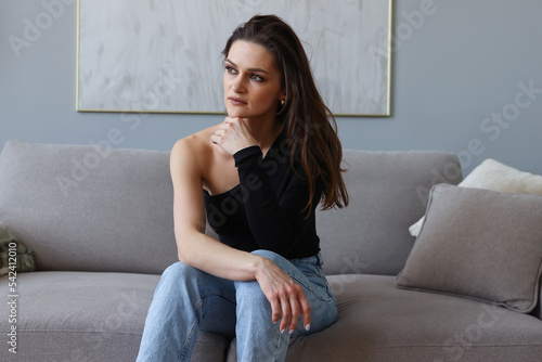 Fashion portrait of a young woman in a black T-shirt and jeans at home