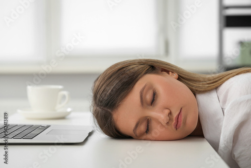 Tired young woman sleeping at workplace in office