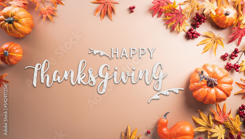 Autumn and thanksgiving decoration concept made from autumn leaves, berry and pumpkin with the text on pastel background.
