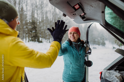 Senior couple near car trunk preparing for winter skiing.