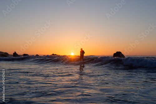 Silhouette of a man surfing at sunset