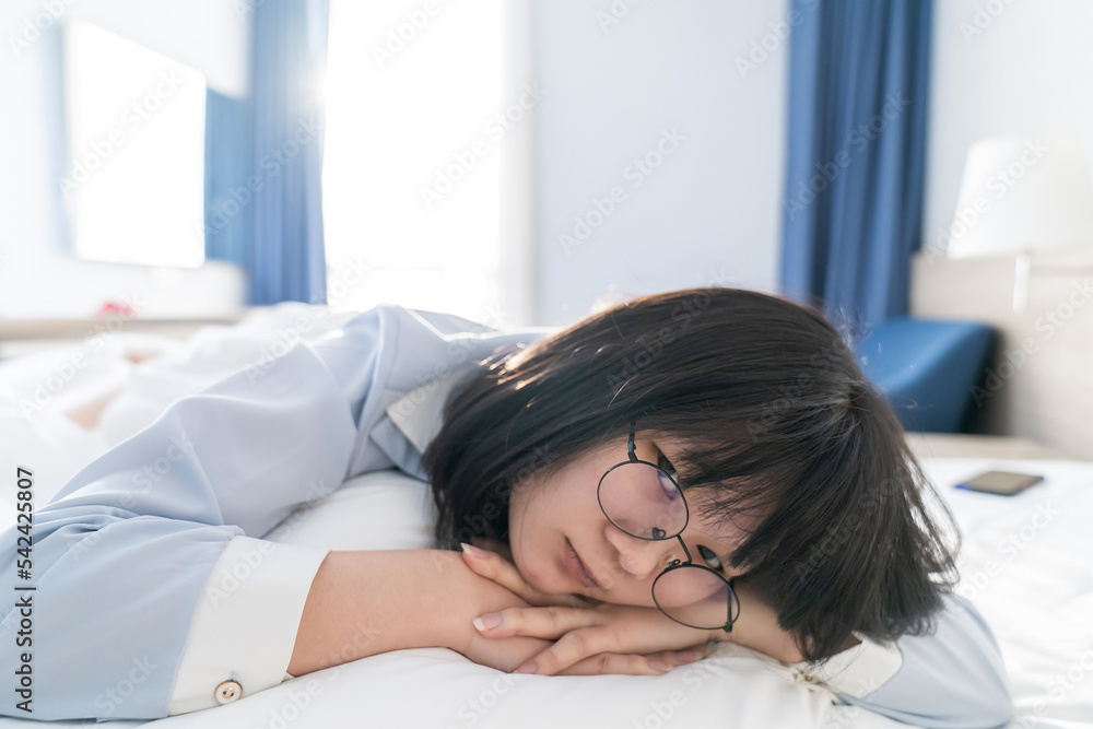 Asian young glasses woman lie on her side on the bed in the morning. Asian young glasses woman lie on her side on the bed in the morning.