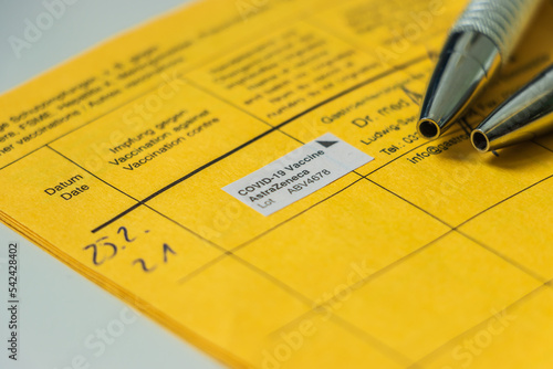 Side view of an open vaccination certificate from the World Health Organization with proof of medical company vaccine against coronavirus. Two ballpoint pens on the vaccination book page