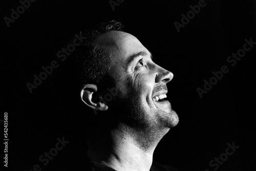 Laughing happy man low key portrait in black and white silhouette in profile looking upwards