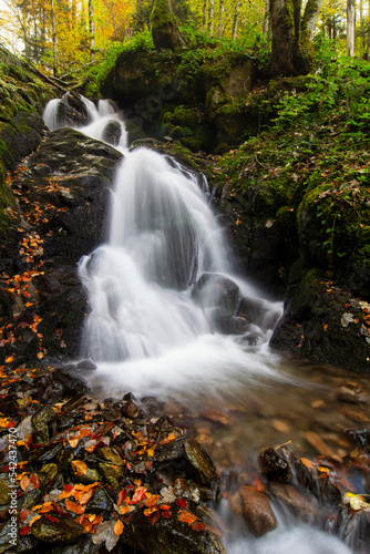 Waterfall flowing through rocks in a deep forest  autumn landscape