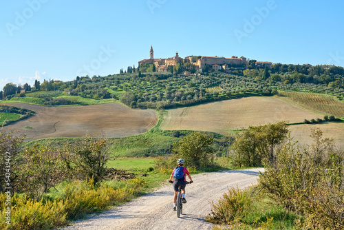 nice senior woman riding her electric mountain bike  in the Ghianti area beow the skyline of the medieval city of Pienza , Tuscany , Italy photo