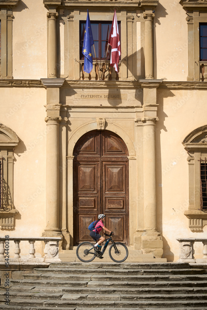 nice woman cycling in front of a historic palace in Arezzo, Tuscany,Italy