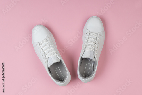 Pair of new white sneakers on pink background