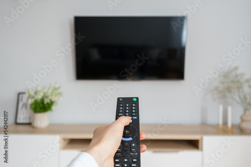 woman watching tv with remote control indoors