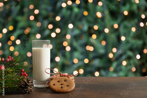 Christmas cookies and milk for Santa Claus in glass near Xmas tree with garland. Christmas card. photo