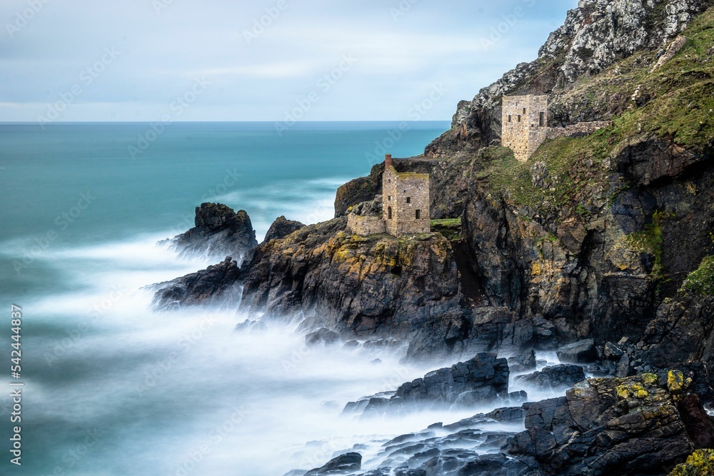 Beautiful shot of ancient buildings on cliffs by a wavy sea coast